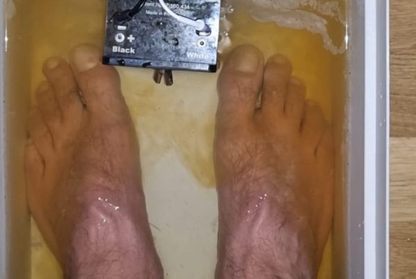 La photo est composée d'une bassine remplie d’eau tiède avec des pieds plongés dedans,
